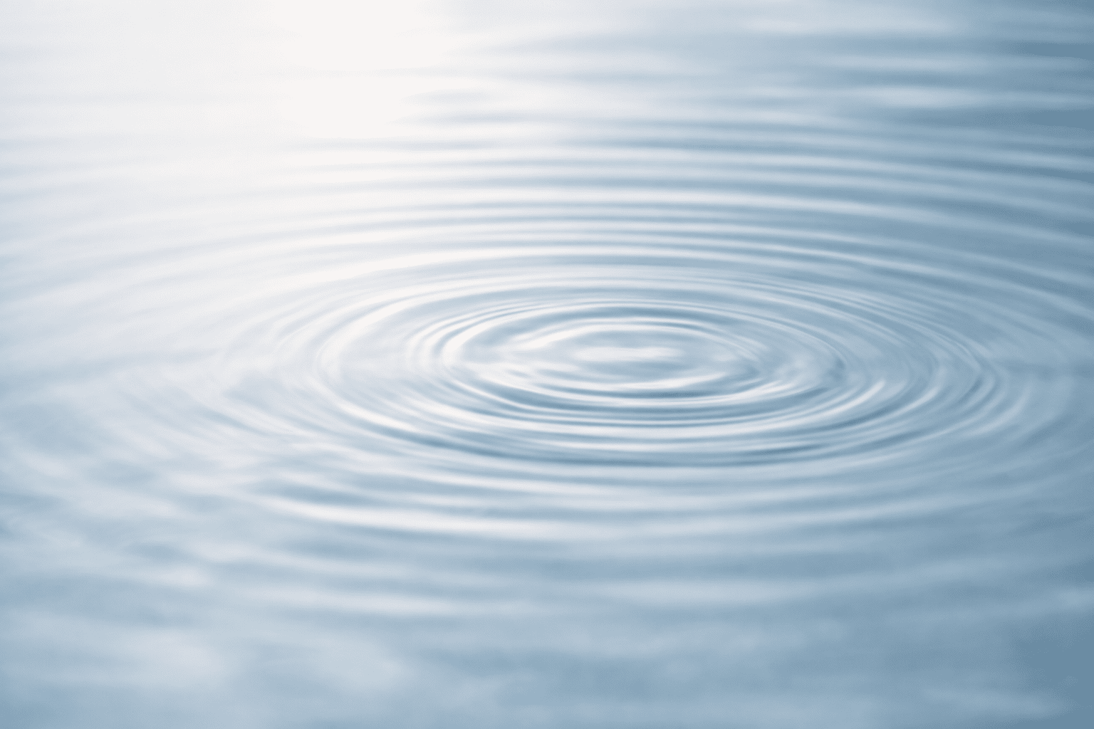 A close-up of gentle concentric ripples spreading across the surface of calm water, evoking the soothing sensation of tapping in emotional freedom technique (EFT).
